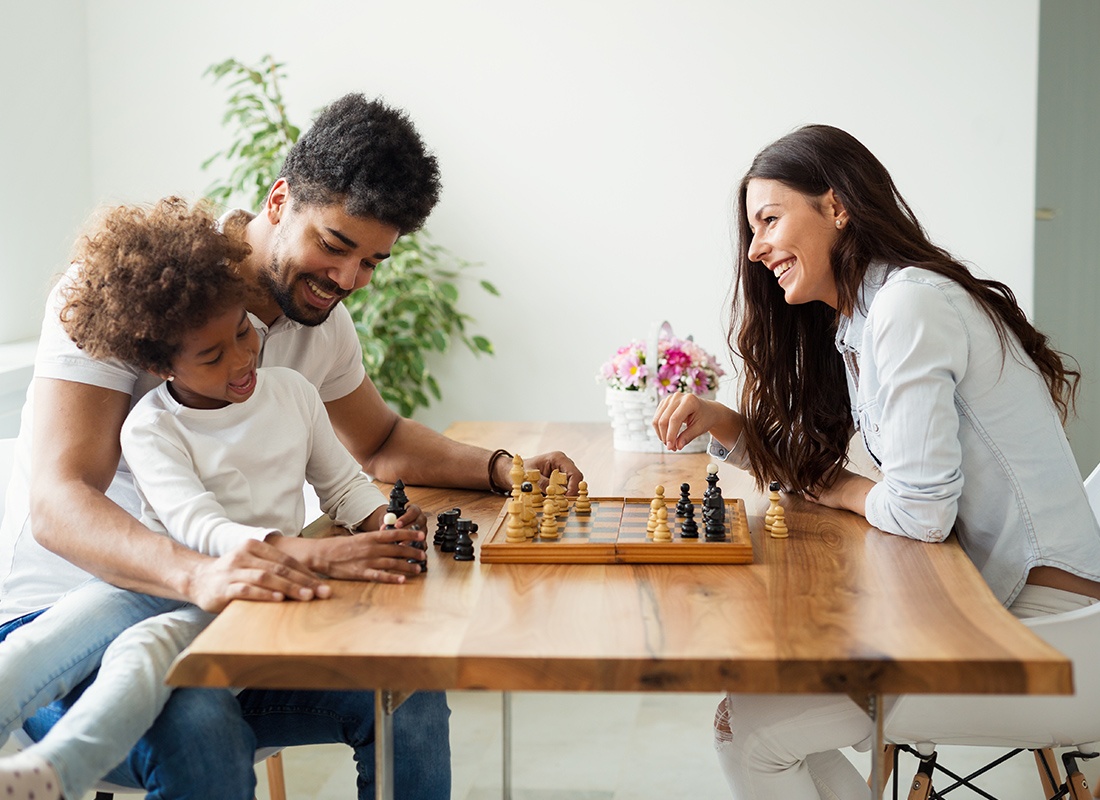 Insurance Solutions - Happy Family Sitting Down Together Playing Chess at Home